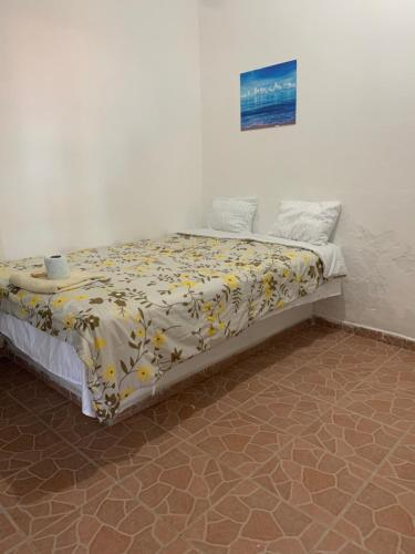 a bed in a room with a yellow and white blanket at Hotel Puerto Real in Paraíso