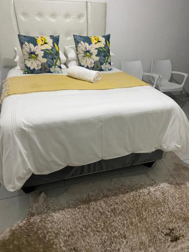 um quarto com uma grande cama branca com almofadas azuis e amarelas em Datty Tatty em Butterworth