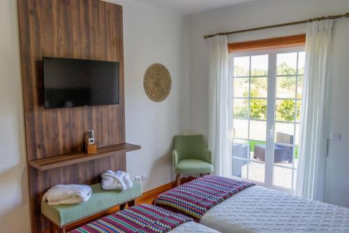 a bedroom with a bed and a television and a window at Quinta Vale Lameiros 