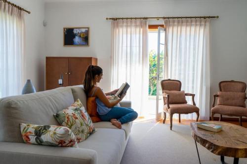 a woman sitting on a couch reading a book at Quinta Vale Lameiros in Abraã