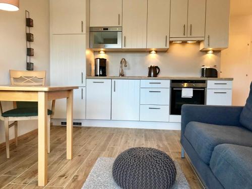 a kitchen with white cabinets and a table and a couch at ZVGB Sproede _ Ferienwohnung Leuch in Ulstrupfeld
