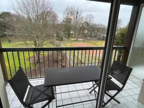 a balcony with a table and chairs and a view of a park at Appart -Rés du Parc-Hardelot-plage in Hardelot-Plage