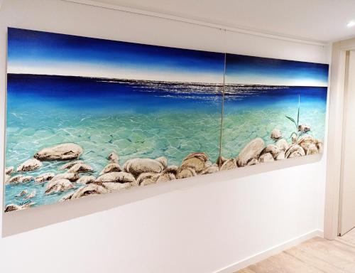 a painting of rocks in the ocean on a wall at Art Studios Gialova Navarino in Gialova