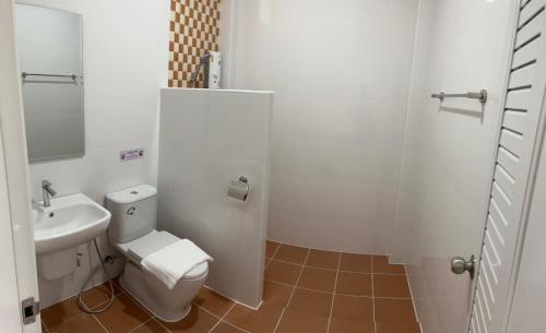 a white bathroom with a toilet and a sink at The P2 Hotel in Mae Sot