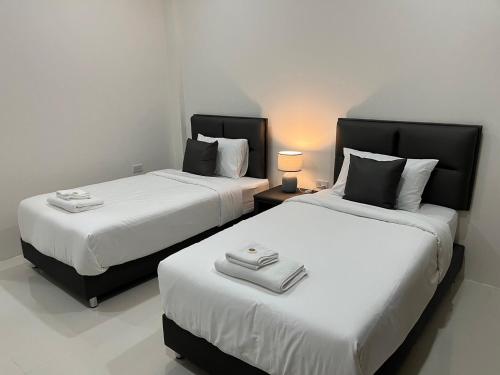 two beds in a white room with two lamps at The P2 Hotel in Mae Sot