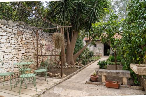 a garden with a table and chairs and a stone wall at Casa Vacanze Alisei in Terlizzi