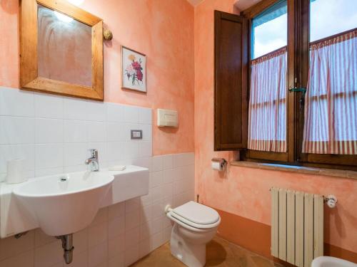 een badkamer met een wastafel, een toilet en een raam bij Agriturismo Mulinaccino in Fabro