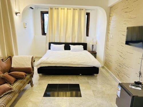 een slaapkamer met een bed en een bank bij Nile Hotel in Dar es Salaam