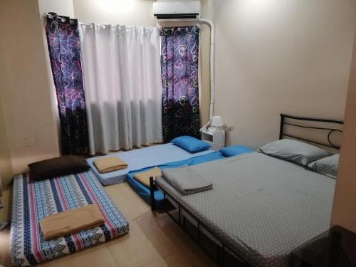 a room with three beds and curtains and a window at JD Homestays CDO in Cagayan de Oro