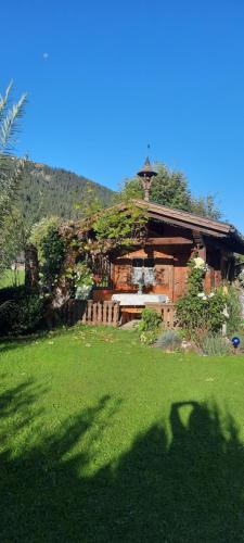 une cabane en rondins avec une pelouse devant elle dans l'établissement Haus Baumgartner, à Schattwald