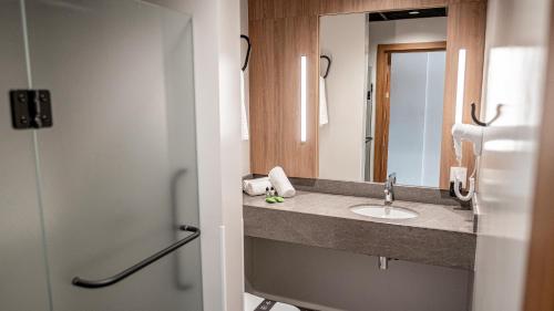 a bathroom with a sink and a mirror at Plaza Hotel & Boulevard Convention - Vale dos Vinhedos in Garibaldi
