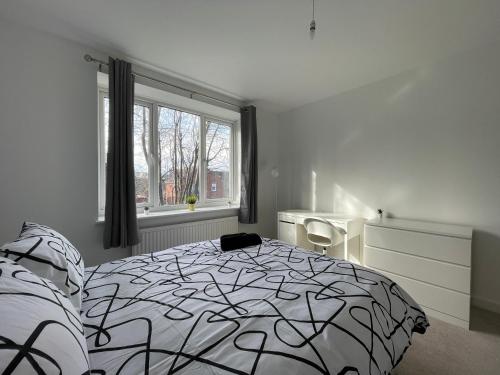 Un dormitorio con una cama en blanco y negro y una ventana en Spacious 2BR Apartment w/Parking Near City Centre, en Sheffield