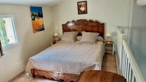 サン・レミ・ド・プロヴァンスにあるLes Lavandins-Gite Magaliのベッドルーム1室(大型ベッド1台、木製ヘッドボード付)
