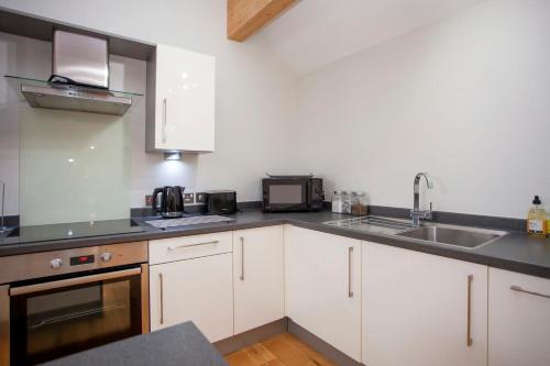 a kitchen with white cabinets and a sink at higgihaus Cabot Mews #32 Sunday - Friday Central Location in Bristol