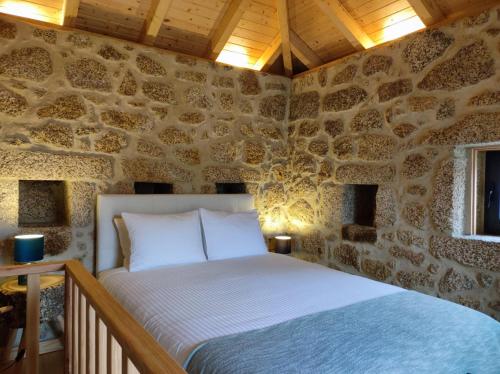 - une chambre avec un lit dans un mur en pierre dans l'établissement Quinta de São Pedro de Vir-a-Corça em Monsanto, à Monsanto