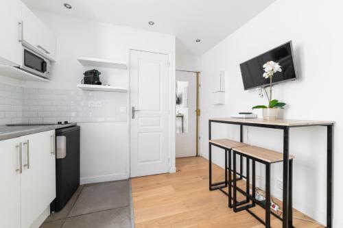 - une cuisine avec un comptoir et une table avec une télévision dans l'établissement Imhost 6 - Charming Appartement Batignolles, à Paris
