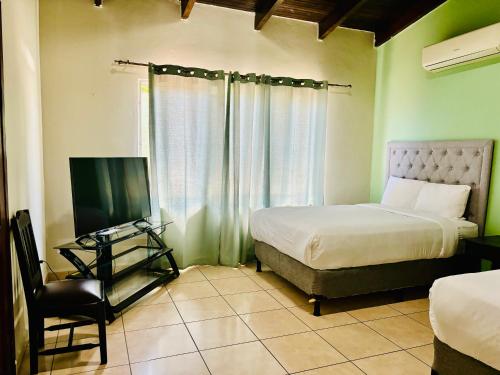 a bedroom with a bed and a television and a chair at Casa Primavera SPS in San Pedro Sula