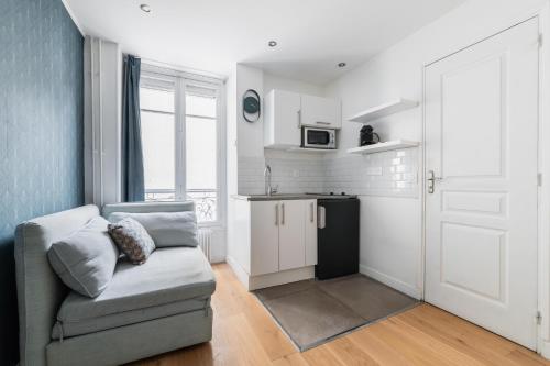 un salon avec un canapé et une cuisine dans l'établissement Imhost 6 - Charming Appartement Batignolles, à Paris