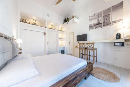 a white bedroom with a bed and a tv at B&B Camera a Sud Iris in Trani