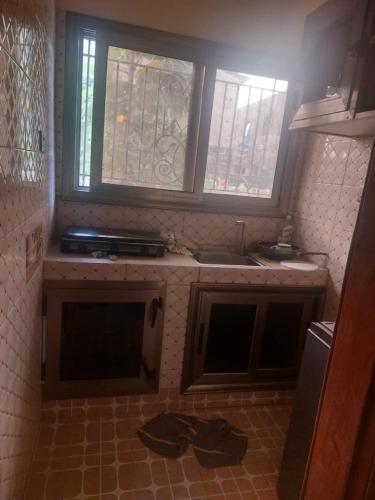 eine Küche mit einem Waschbecken und zwei Fenstern darin in der Unterkunft Castor in Ziguinchor