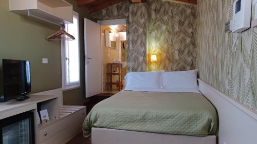niewielka sypialnia z łóżkiem i telewizorem w obiekcie B&B Opera Prima w Weronie