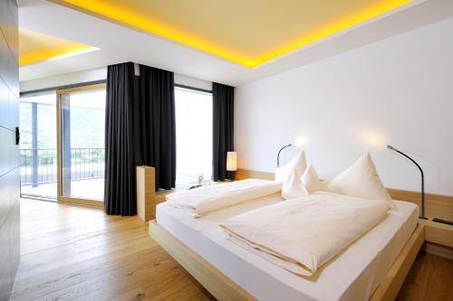 1 dormitorio con cama blanca y techo amarillo en Bio & Wellnesshotel Pazeider - Healing Garden above Meran, en Marlengo