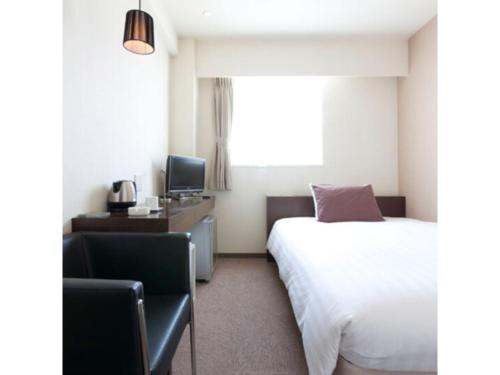 a hotel room with a bed and a chair and a television at Hotel day by day - Vacation STAY 93900 in Hamamatsu