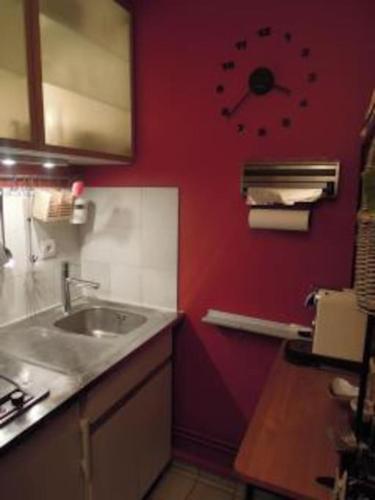 une cuisine avec un évier et une horloge murale dans l'établissement Studio très calme Montparnasse, à Paris