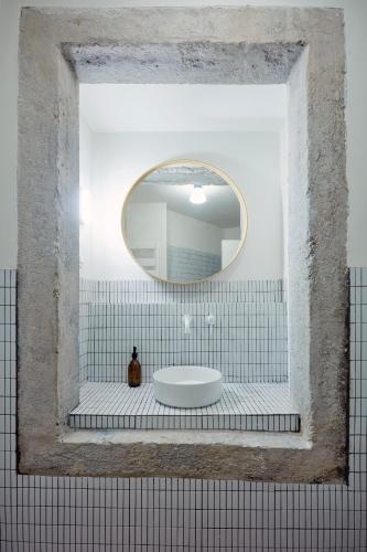 a bathroom with a round mirror and a sink at Casa Pavão Lisboa in Lisbon