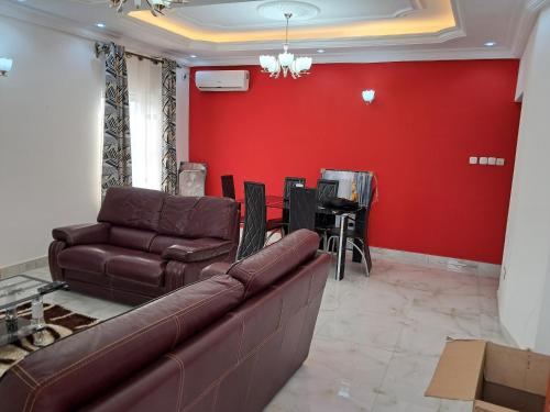 a living room with a couch and a red wall at APPARTEMENT NEW STANDING CITE CHIRAC YASSA in Yapoma