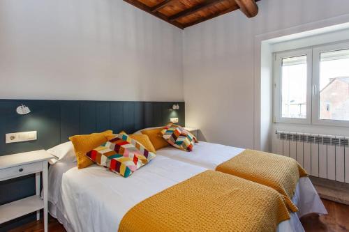 a bedroom with a large bed with colorful pillows at Casa do Cesteiro in Santiago de Compostela