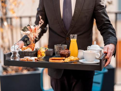 Un hombre con traje sosteniendo una bandeja de comida para el desayuno. en Grand Hotel Lafayette, en París