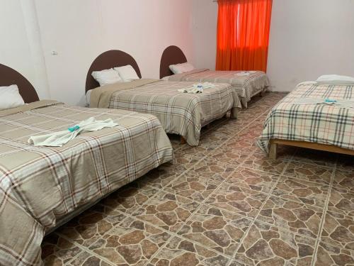 three beds sitting in a room with a tile floor at Hotel Puerto Real in Paraíso