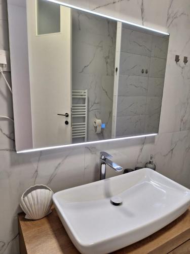 a bathroom with a white sink and a mirror at Apartman DJ in Đakovo