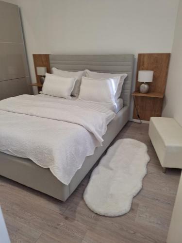 Un dormitorio con una cama grande con sábanas y almohadas blancas. en Apartman DJ, en Ðakovo