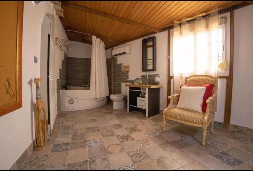 y baño con bañera, aseo y silla. en villa alba ibiza en Santa Eulalia del Río