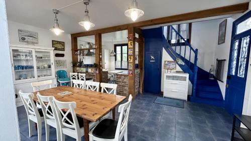 ein Esszimmer mit einem Holztisch und einer blauen Treppe in der Unterkunft Sans Souci, maison familiale pour 8 personnes in Cayeux-sur-Mer