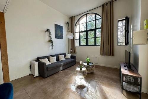 sala de estar con sofá y TV en Suites Rive Gauche - Impressionnistes Barbizon, en Barbizon