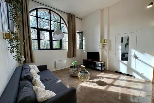 a living room with a blue couch and a large window at Impressionnistes Barbizon in Barbizon