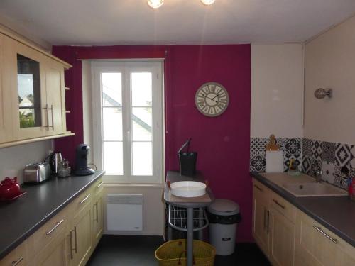 eine Küche mit einem Fenster und einer Uhr an der Wand in der Unterkunft Location Ker Bihan in Saint-Lunaire