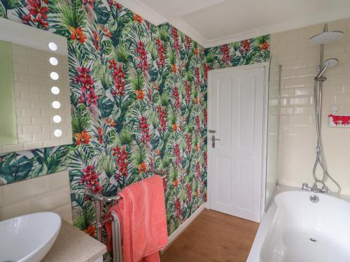 a bathroom with a tropical wallpaper on the wall at Wayside in Seaton