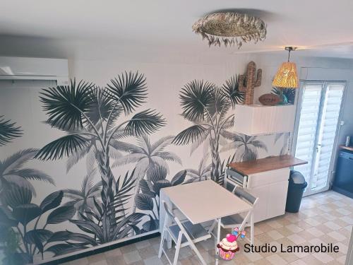 una cocina con un mural de palmeras en la pared en Narbonne Studio Lamarobile avec jardin et terrasse proche des Grands Buffets, du centre ville et de la gare, en Narbona