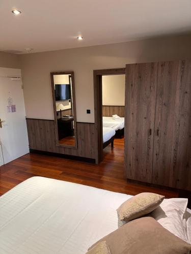 a bedroom with two beds and a large mirror at Logis Hotel Des Bains in Gérardmer
