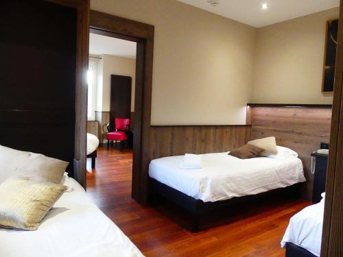 a hotel room with two beds and a mirror at Logis Hotel Des Bains in Gérardmer