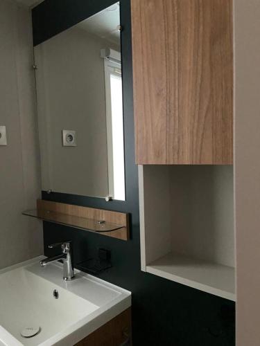 une salle de bain avec un lavabo et un miroir dans l'établissement Mobil home Aventura 6-8 personnes tout confort, à Saint-Brévin-les-Pins