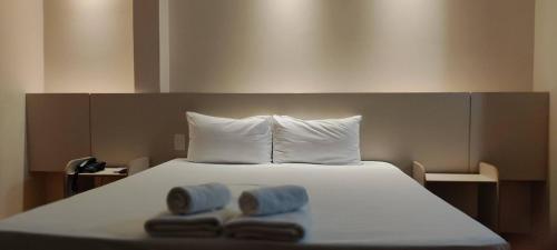 a bed with two towels on top of it at Vespasiano Hotel Telêmaco Borba in Telêmaco Borba