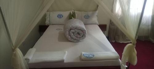 a white bed with a pillow on top of it at WAYPOINT SUITES HOTEL in Kabale