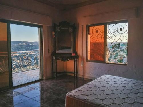 a bedroom with a bed and a mirror and windows at Breeze House in Kafr Khall