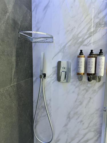 a bathroom with a shower with three bottles of soap at Le Suite Piazza Nuova in Foggia