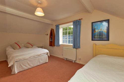 1 dormitorio con 2 camas y ventana en Finest Retreats - The Coach House at Holyford Farm en Colyford